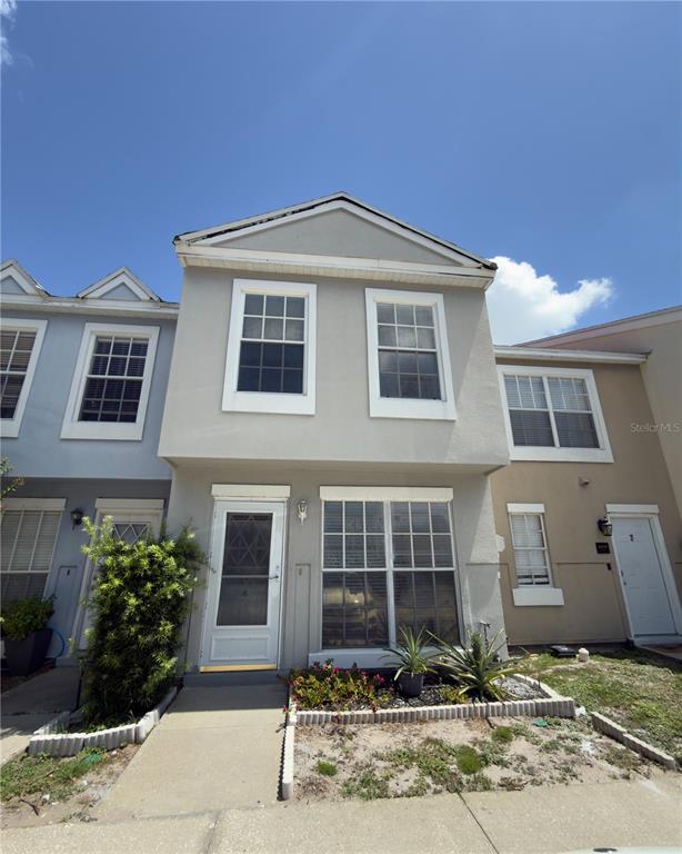 A two-story townhouse exterior features a light gray facade, white trim, and a concrete walkway — 6630 121ST AVENUE UNIT 6, LARGO, FL