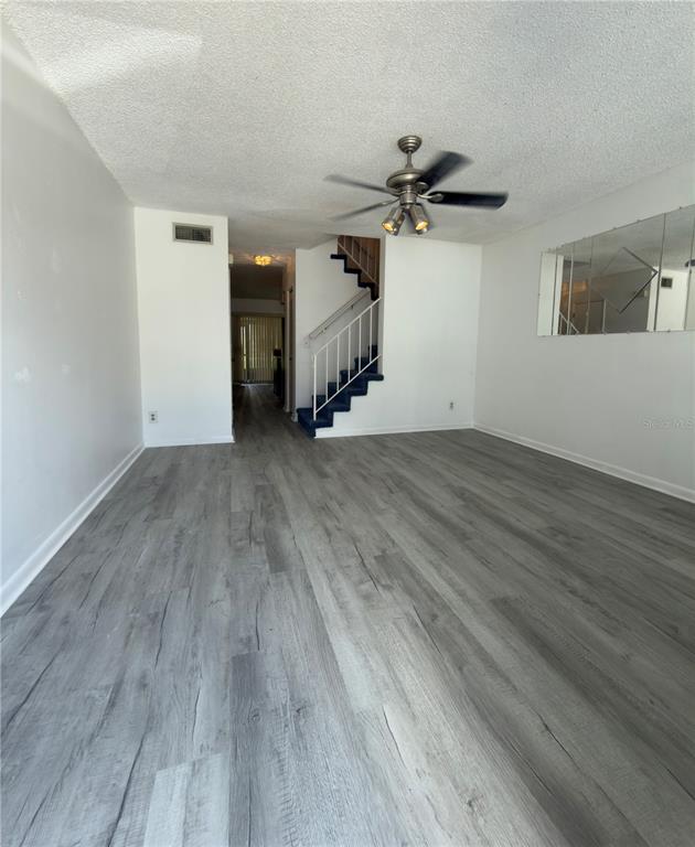 A living room features gray wood-look flooring, a ceiling fan, and a staircase with blue carpet — 6630 121ST AVENUE UNIT 6, LARGO, FL