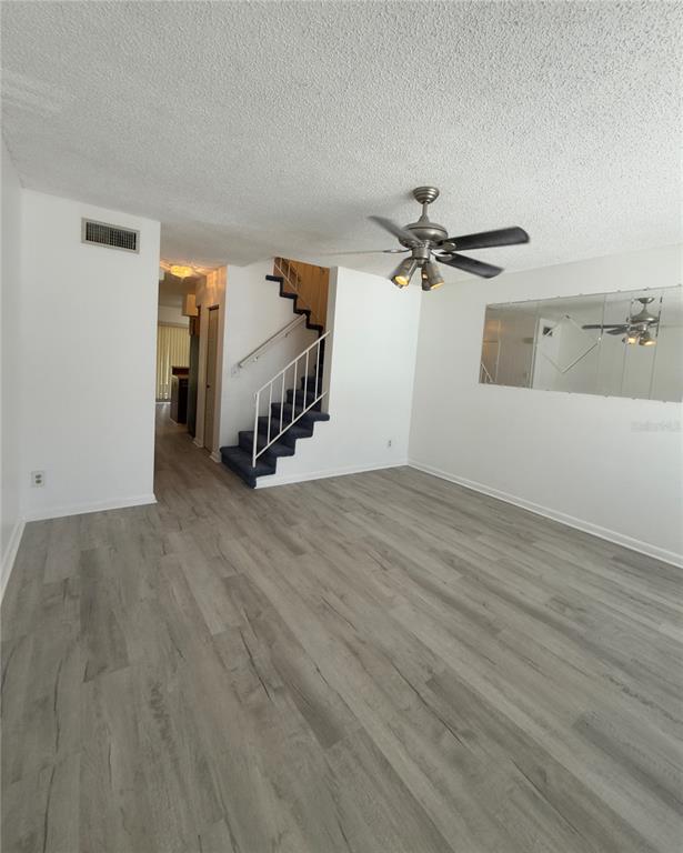 A living room features light wood-look flooring, a ceiling fan, and stairs with blue carpeting — 6630 121ST AVENUE UNIT 6, LARGO, FL