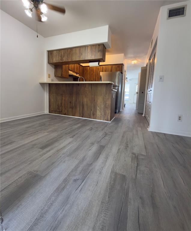 A kitchen with wood-look cabinets and a breakfast bar overlooks a room with gray flooring — 6630 121ST AVENUE UNIT 6, LARGO, FL