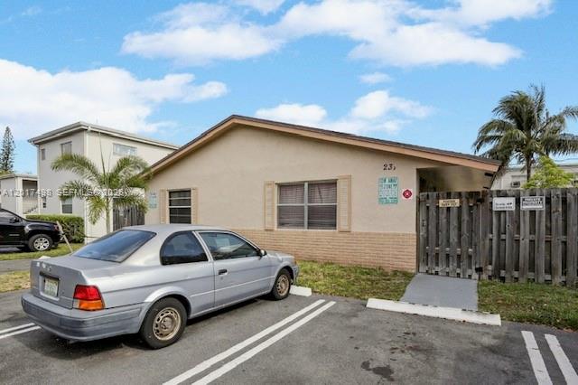 A silver sedan is parked in front of a single-story building with a wooden fence — 231 SW 8th Ct, Pompano Beach FL 33060, POMPANO BEACH, FL