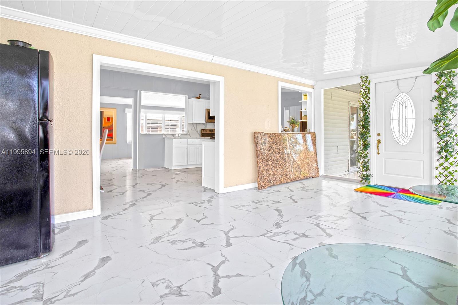 A room with white marble-patterned tile floors, a black refrigerator, and a granite slab — 5103 NW 1st Way, Deerfield Beach FL 33064, DEERFIELD BEACH, FL