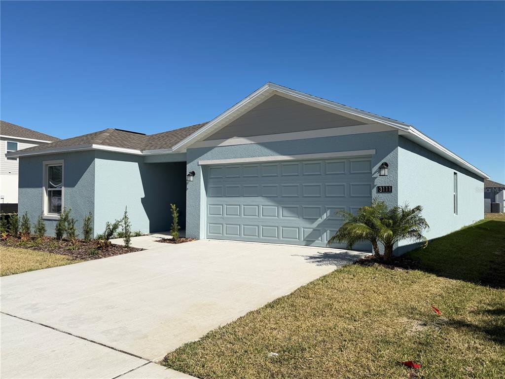 A light blue single-story house features a two-car garage and a concrete driveway — 3111 TOTEM ROAD, EAGLE LAKE, FL