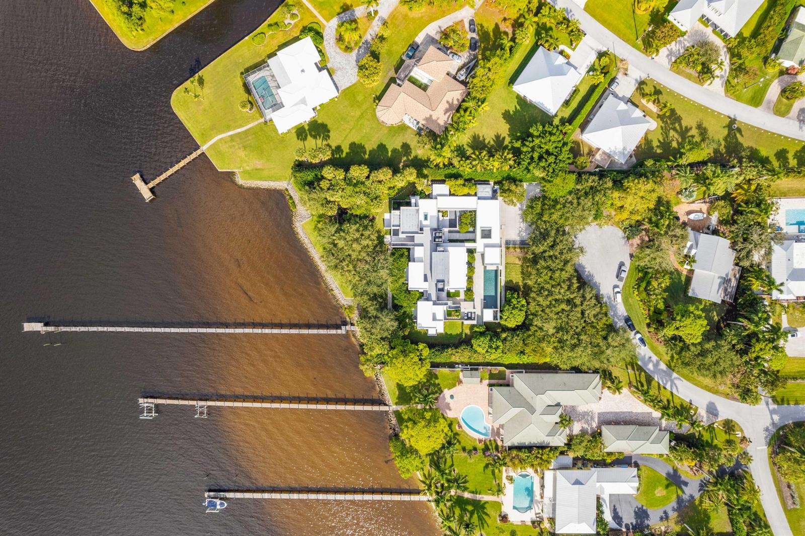 An aerial view shows several waterfront houses with private docks and swimming pools — 1924 NW Shore Terrace, Stuart FL 34994, STUART, FL
