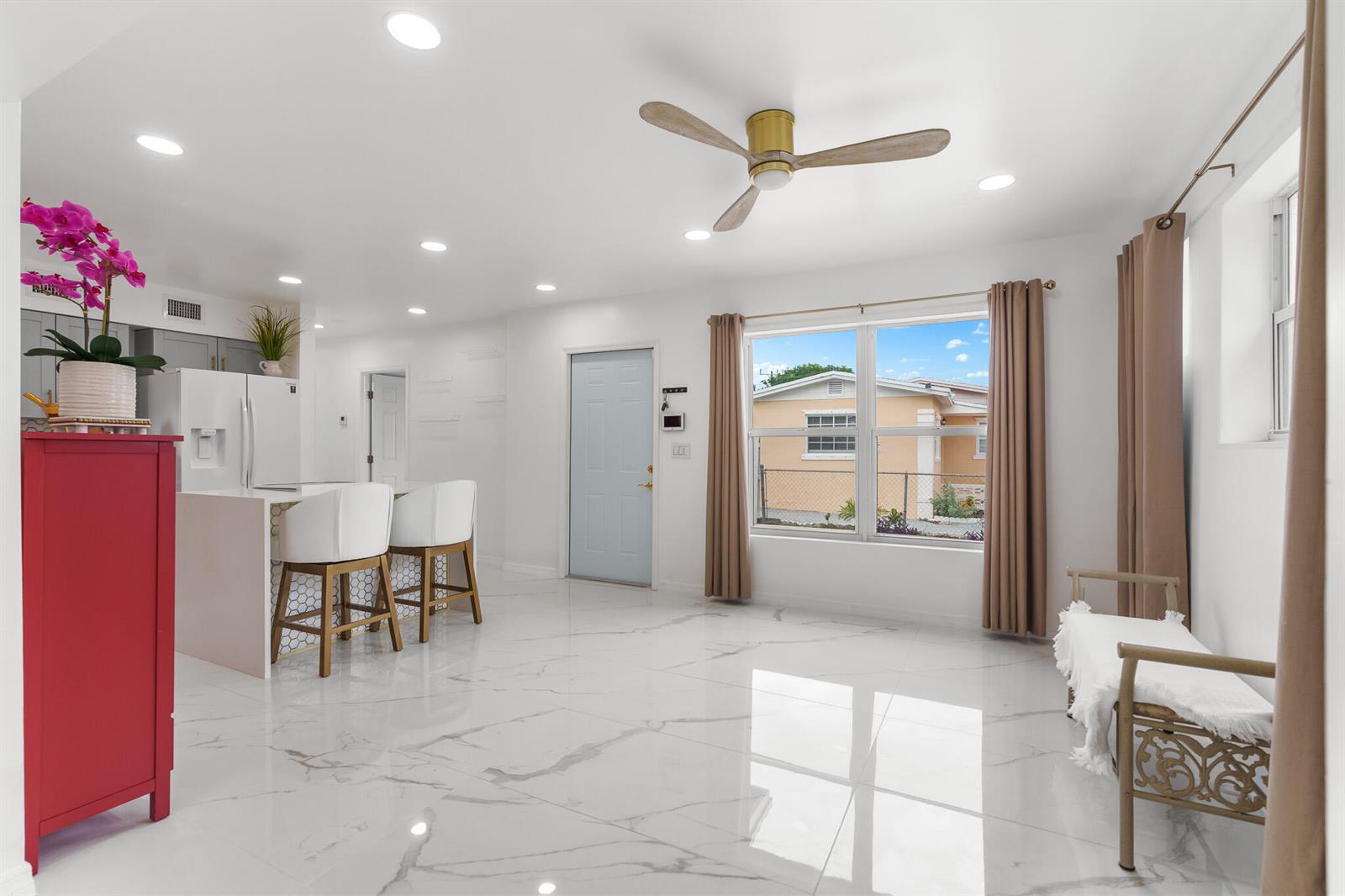 A bright, open-concept kitchen and living area features white marble floors and a ceiling fan — 201 NE 28th Court, Boynton Beach FL 33435, BOYNTON BEACH, FL