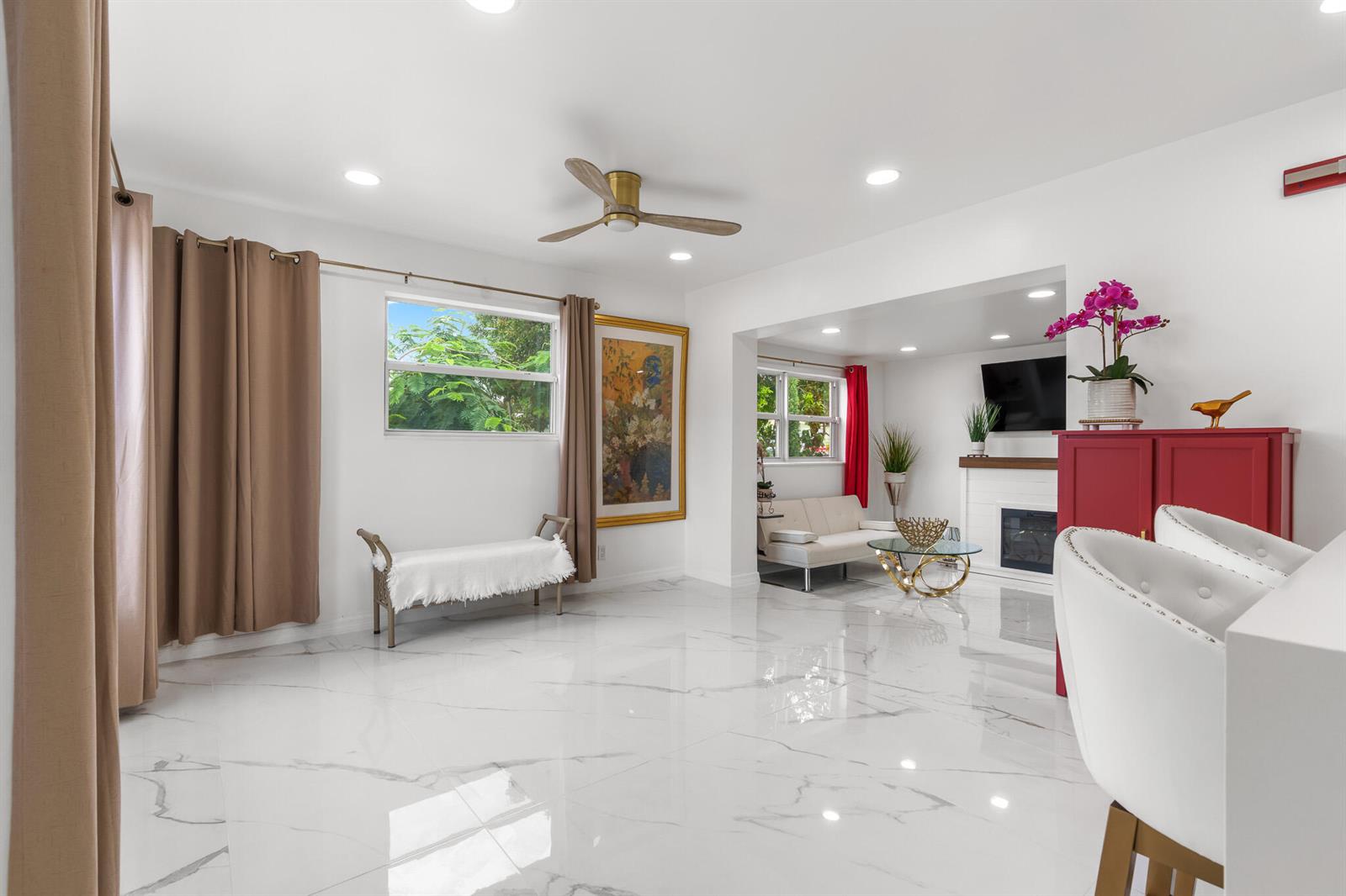 A bright living room features white marble floors, a ceiling fan, and a fireplace — 201 NE 28th Court, Boynton Beach FL 33435, BOYNTON BEACH, FL