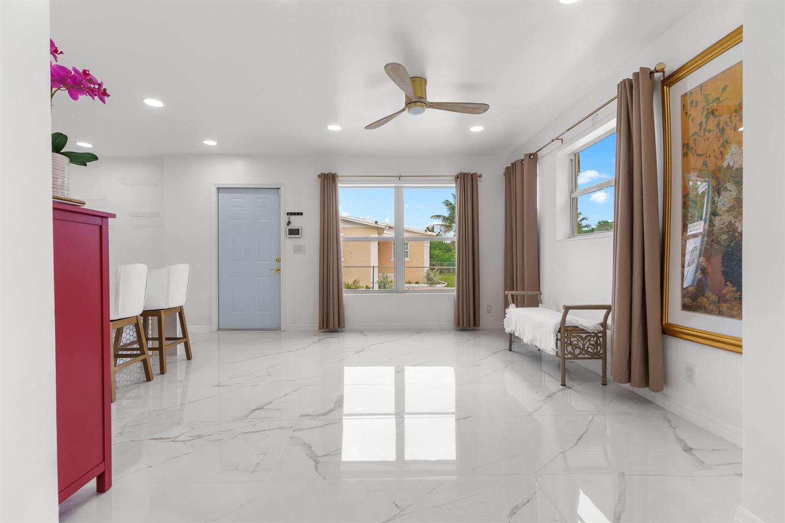 A bright room with white marble-look tile flooring, a ceiling fan, and a light blue door — 201 NE 28th Court, Boynton Beach FL 33435, BOYNTON BEACH, FL