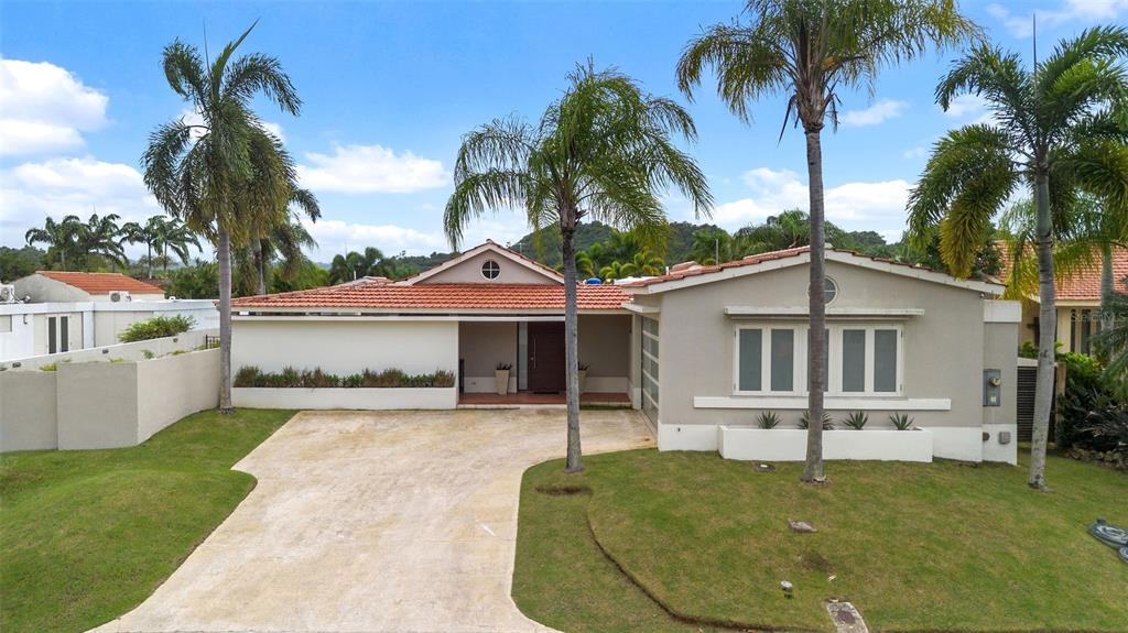 A single-story house with a terracotta tile roof, a concrete driveway, and several palm trees — 170 CAMINO DE LOS JAZMINES, DORADO, PR