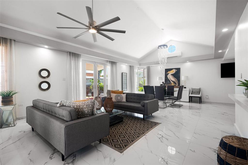 A bright, open-concept living and dining area features white marble floors and a vaulted ceiling — 170 CAMINO DE LOS JAZMINES, DORADO, PR