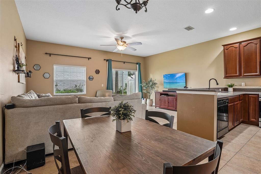 An open-concept living and dining area features a wooden table, beige sofa, and kitchen cabinets — 1329 HERITAGE COMMONS DRIVE, WINTER SPRINGS, FL