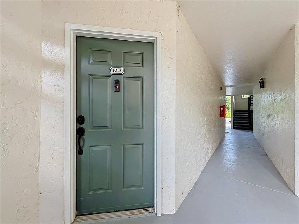 A green front door labeled 1013 opens into a hallway with a fire extinguisher — 5144 CONROY ROAD UNIT 13, ORLANDO, FL