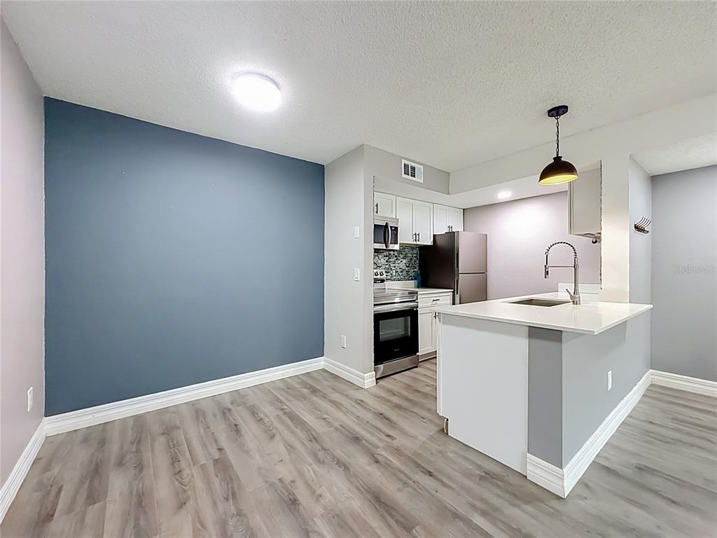 A kitchen with white cabinets, stainless steel appliances, and a blue accent wall — 5144 CONROY ROAD UNIT 13, ORLANDO, FL
