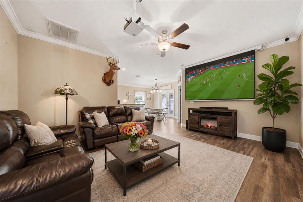 A living room features brown leather sofas, a large projector screen, and a fiddle-leaf fig — 362 LAKE STREET, UMATILLA, FL