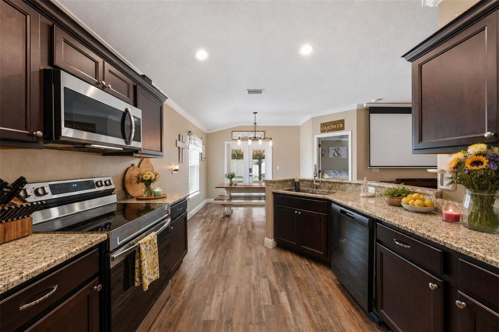 A kitchen with dark wood cabinets, granite countertops, stainless steel appliances, and wood-look flooring — 362 LAKE STREET, UMATILLA, FL