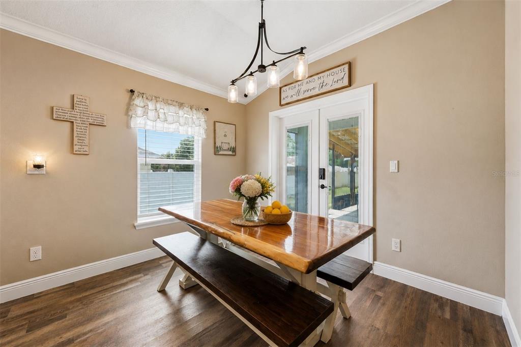 A dining room features a wooden table with benches, a chandelier, and a glass door — 362 LAKE STREET, UMATILLA, FL