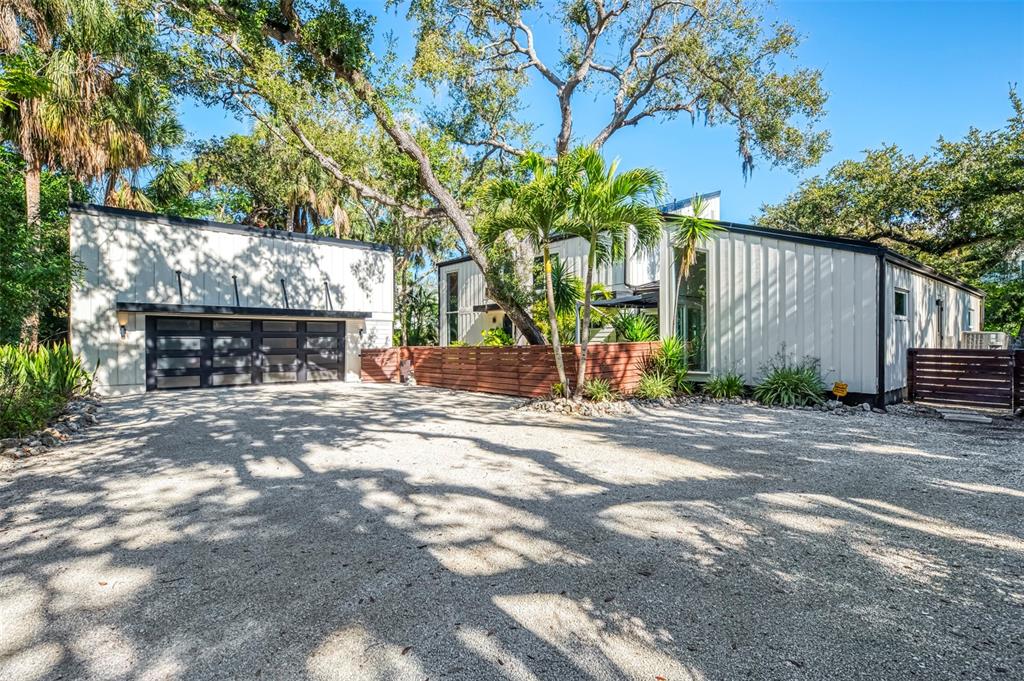 A modern house with white vertical siding, a detached garage, and a gravel driveway — 5303 HIDDEN HARBOR ROAD, SARASOTA, FL