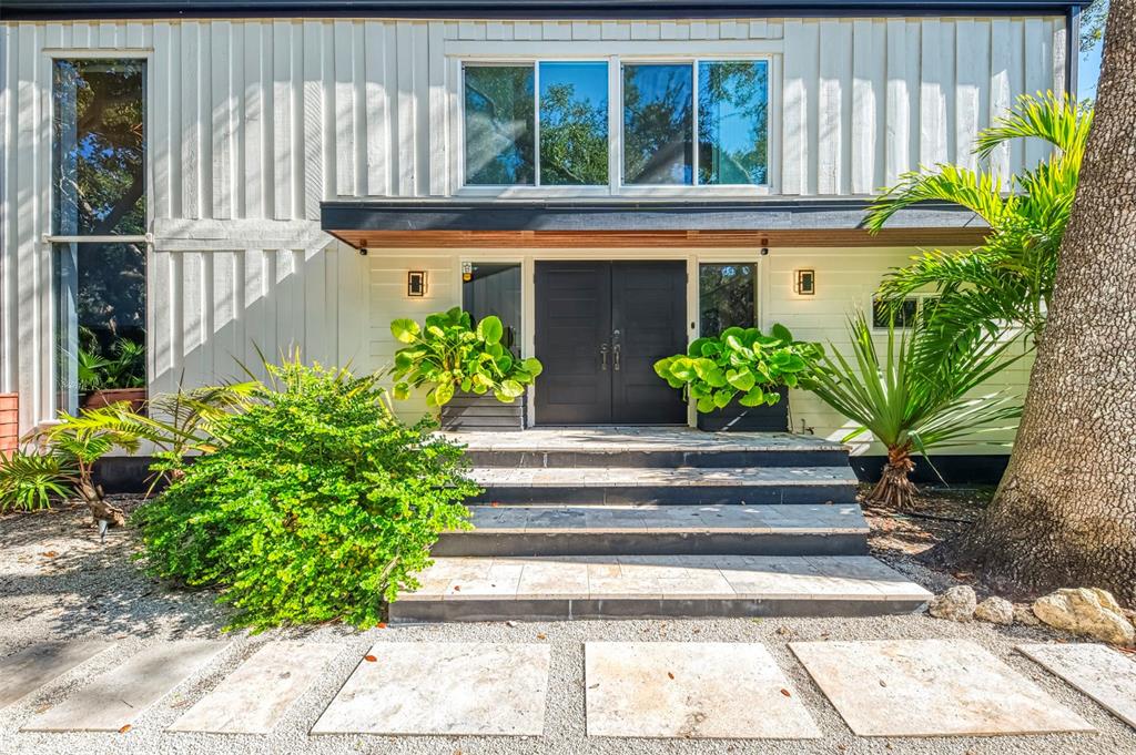 The exterior of a house features a double front door, stone steps, and vertical siding — 5303 HIDDEN HARBOR ROAD, SARASOTA, FL