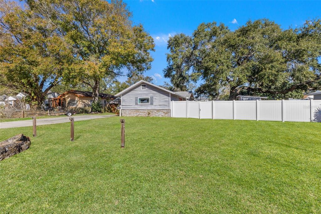 A gray house with a brick base sits behind a white vinyl fence and lawn — 1747 26TH AVENUE N, ST PETERSBURG, FL