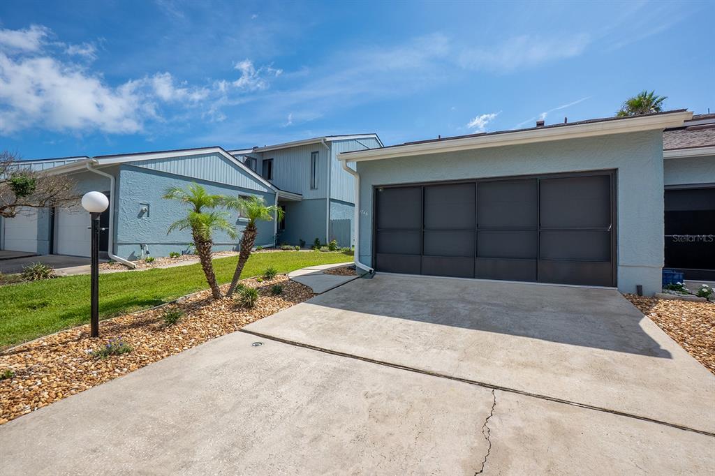 A light blue house exterior features a dark gray garage door and a concrete driveway — 1746 WINDSONG CIRCLE, FLAGLER BEACH, FL