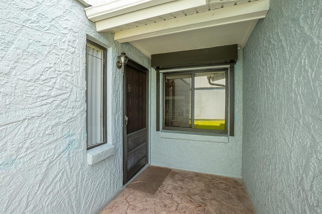 A covered entryway features textured light blue walls, a brown door, and a stone-patterned floor — 1746 WINDSONG CIRCLE, FLAGLER BEACH, FL
