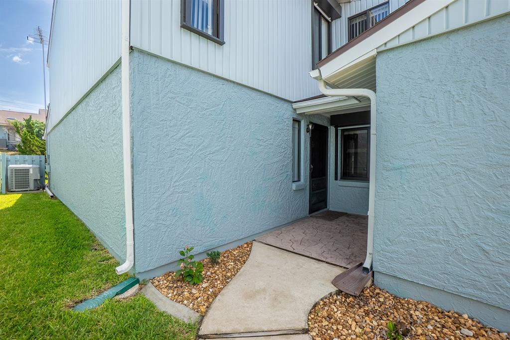 A light blue stucco exterior features a concrete walkway leading to a recessed front entrance — 1746 WINDSONG CIRCLE, FLAGLER BEACH, FL