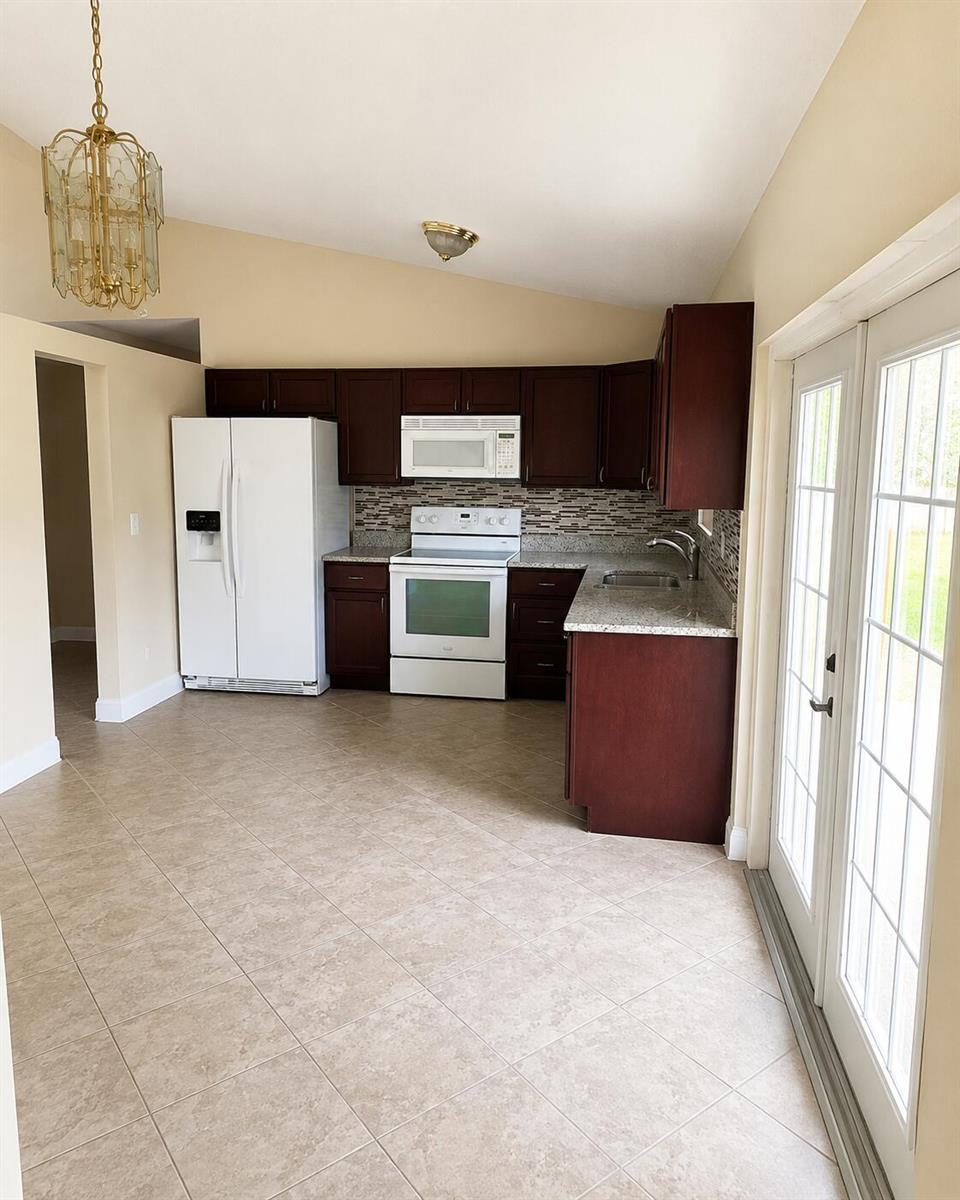 A kitchen with dark wood cabinets, white appliances, granite countertops, and tile flooring — 4231 SW 55th Avenue, Davie FL 33314, DAVIE, FL