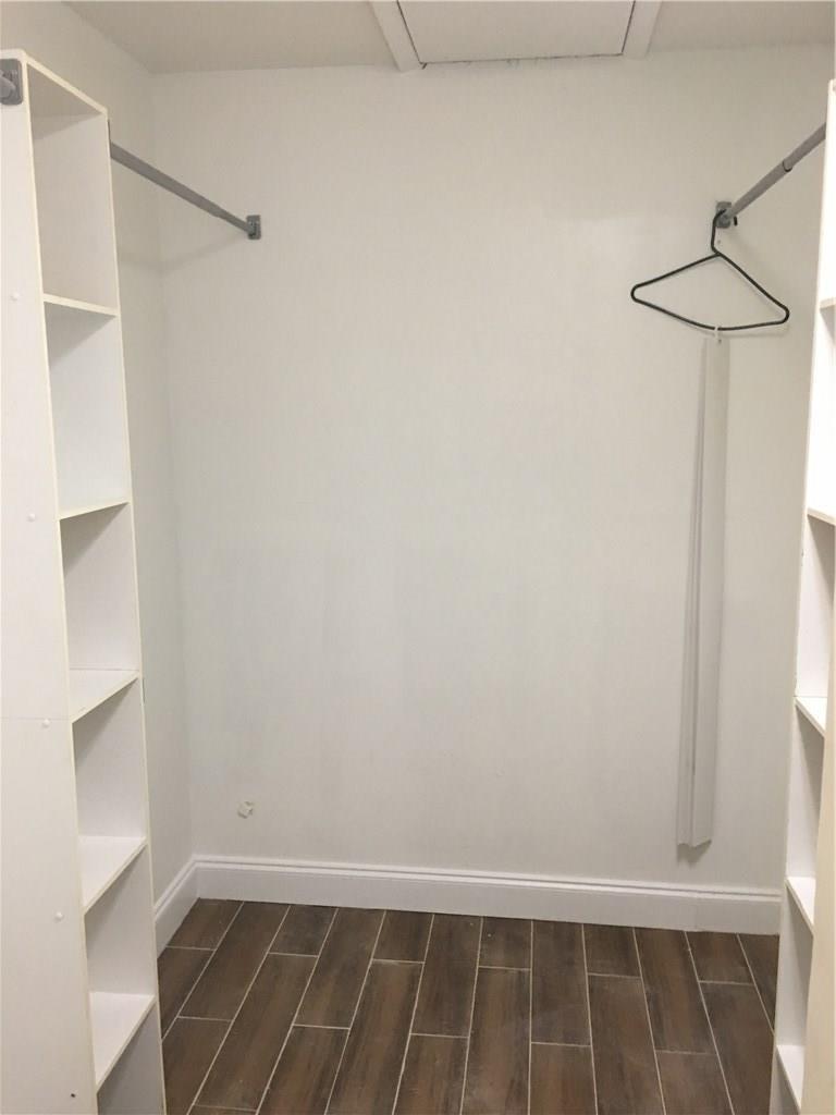A walk-in closet with white shelving units, hanging rods, and wood-look tile flooring — 4231 SW 55th Avenue, Davie FL 33314, DAVIE, FL