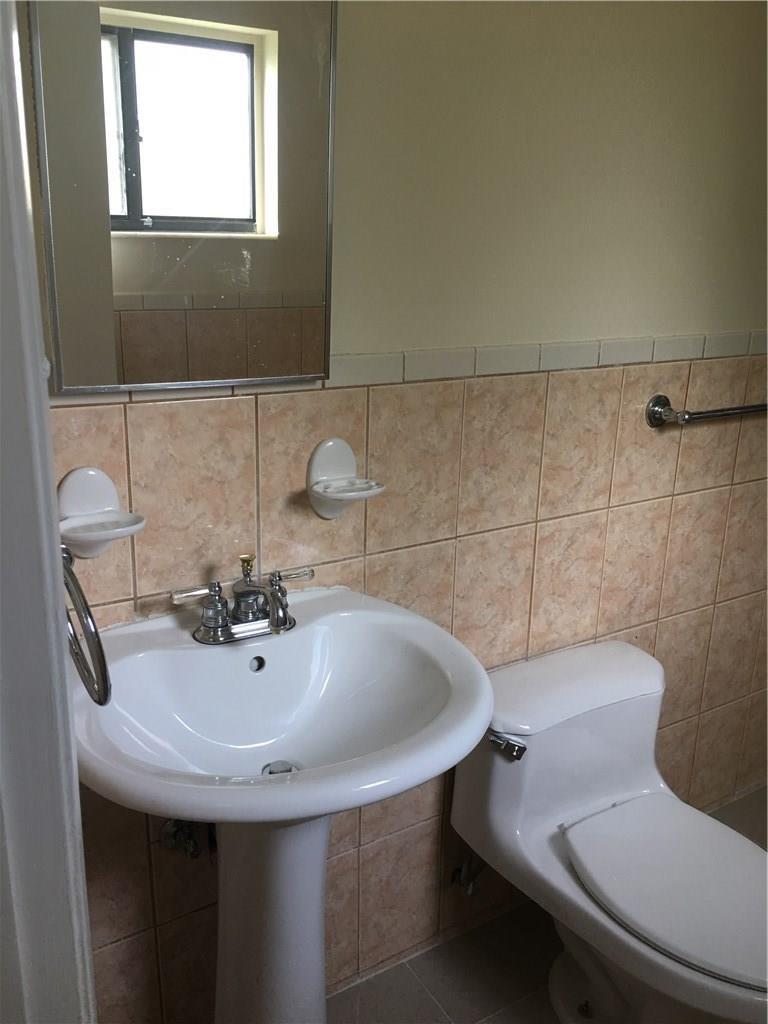 A bathroom features a pedestal sink, a toilet, and beige wall tiles — 4231 SW 55th Avenue, Davie FL 33314, DAVIE, FL