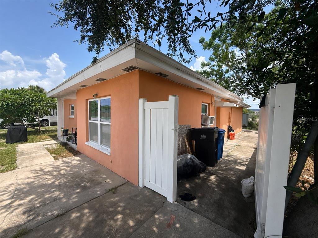 An exterior view of an orange stucco house with a white gate and concrete driveway — 7507 W CARACAS STREET, TAMPA, FL