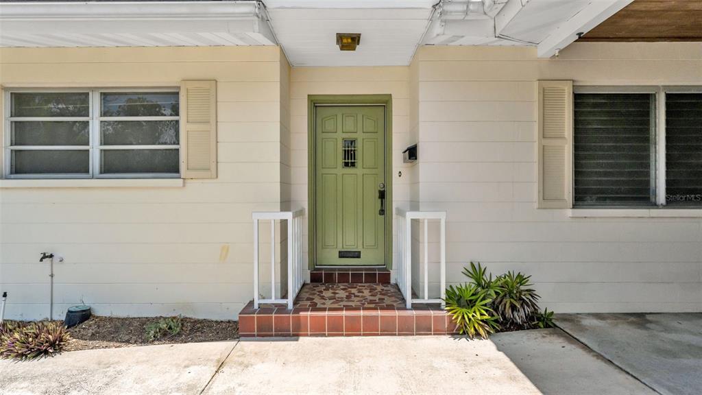 A light green front door with a small window is centered between two windows — 2303 COVENTRY AVENUE, LAKELAND, FL