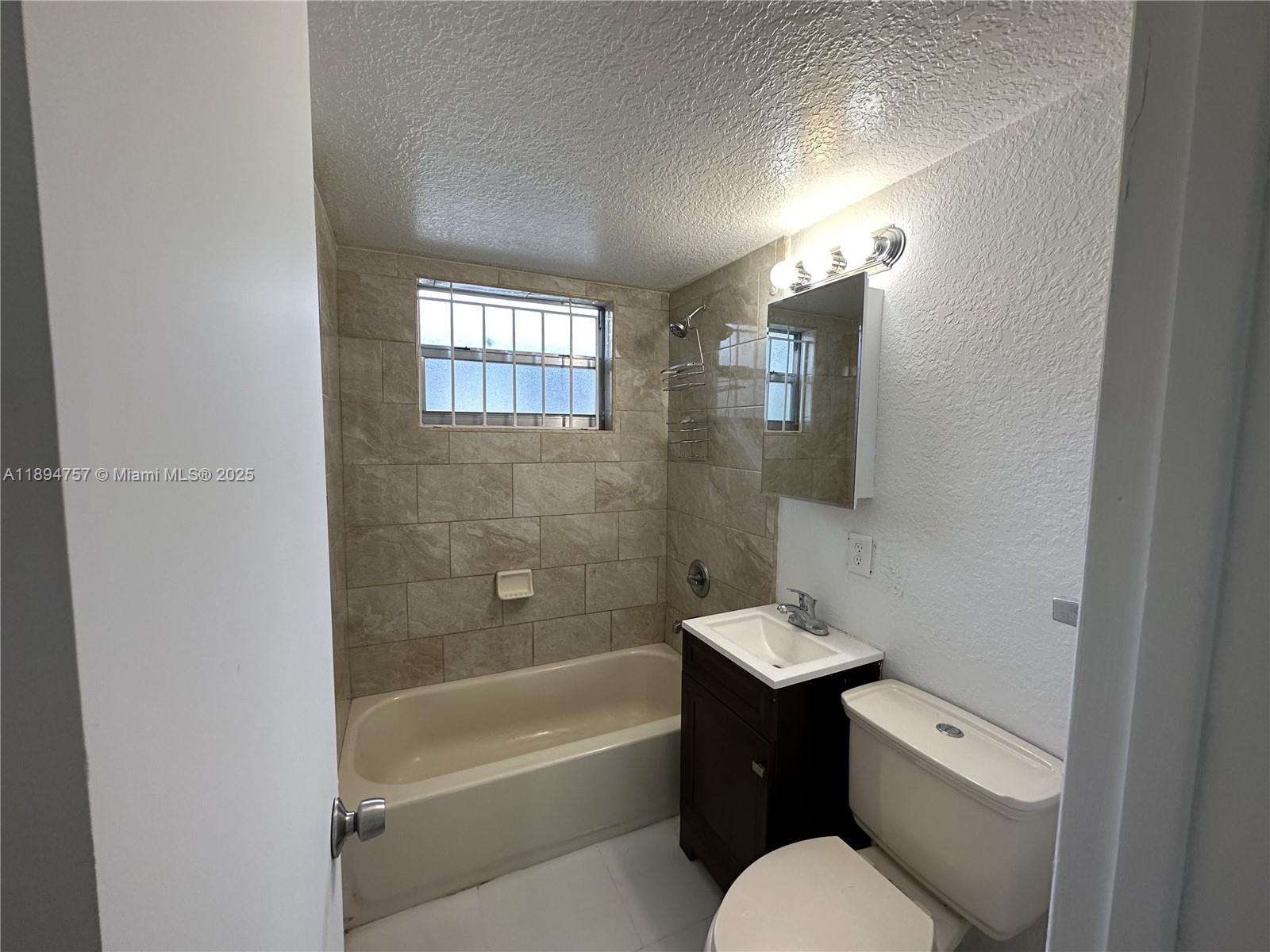 A bathroom features a beige bathtub with tiled walls, a vanity, and a toilet — 1851 Ali Baba Ave # 4, Opa-Locka FL 33054, OPA-LOCKA, FL