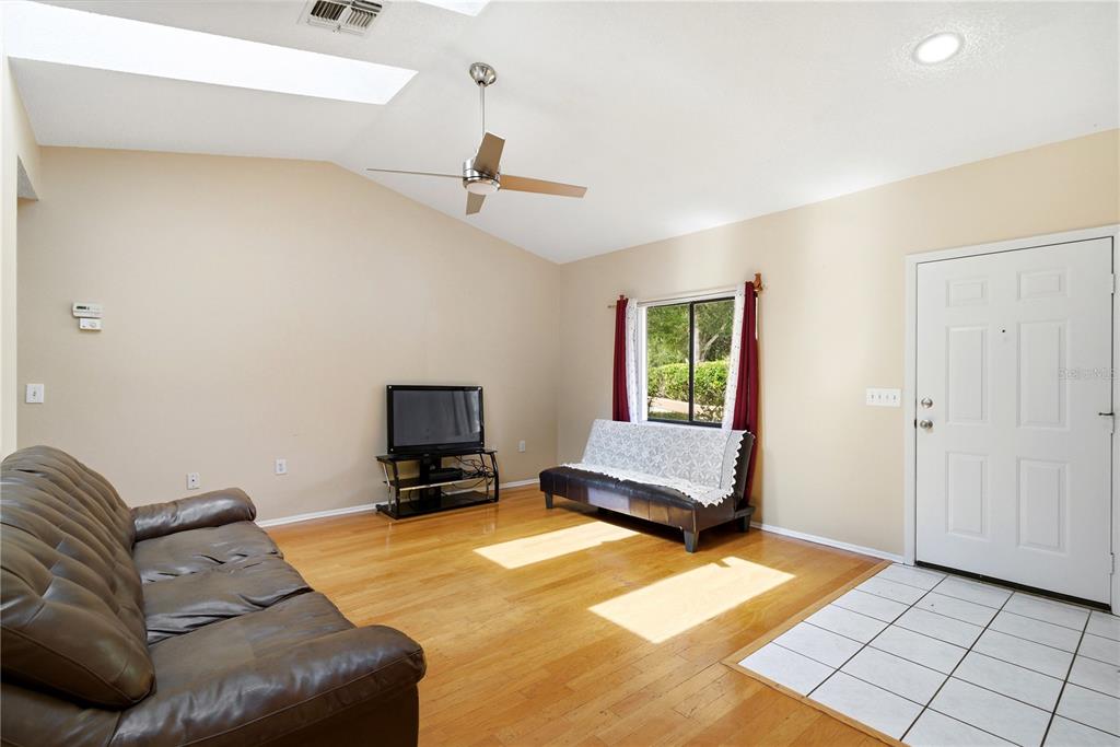 A living room with hardwood floors, a vaulted ceiling, a ceiling fan, and a front door — 8160 STURBRIDGE COURT UNIT 8160, WEEKI WACHEE, FL
