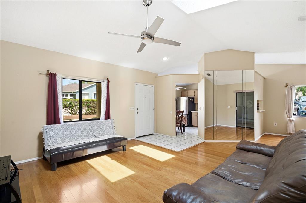 A living room features hardwood floors, a ceiling fan, a sofa, and mirrored closet doors — 8160 STURBRIDGE COURT UNIT 8160, WEEKI WACHEE, FL