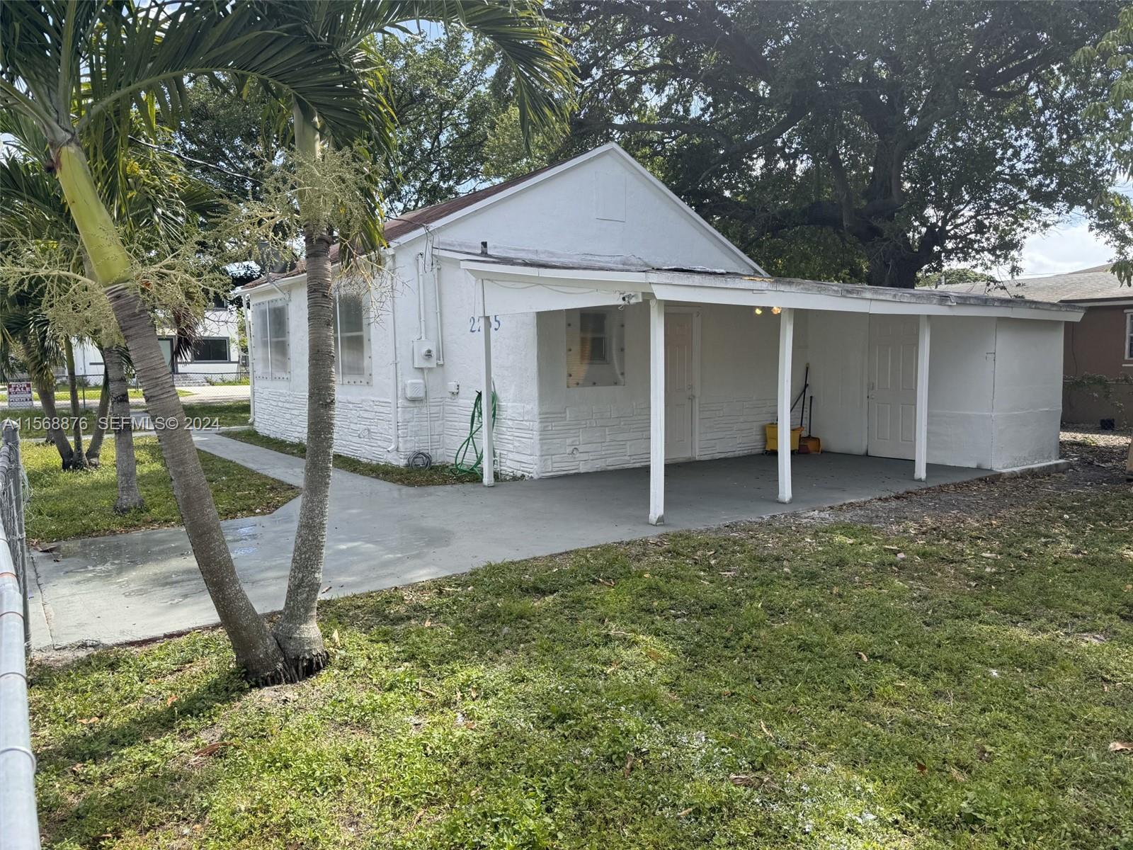 A white single-story house features a covered carport and a concrete walkway — 2255 NW 63rd St, Miami FL 33147, MIAMI, FL