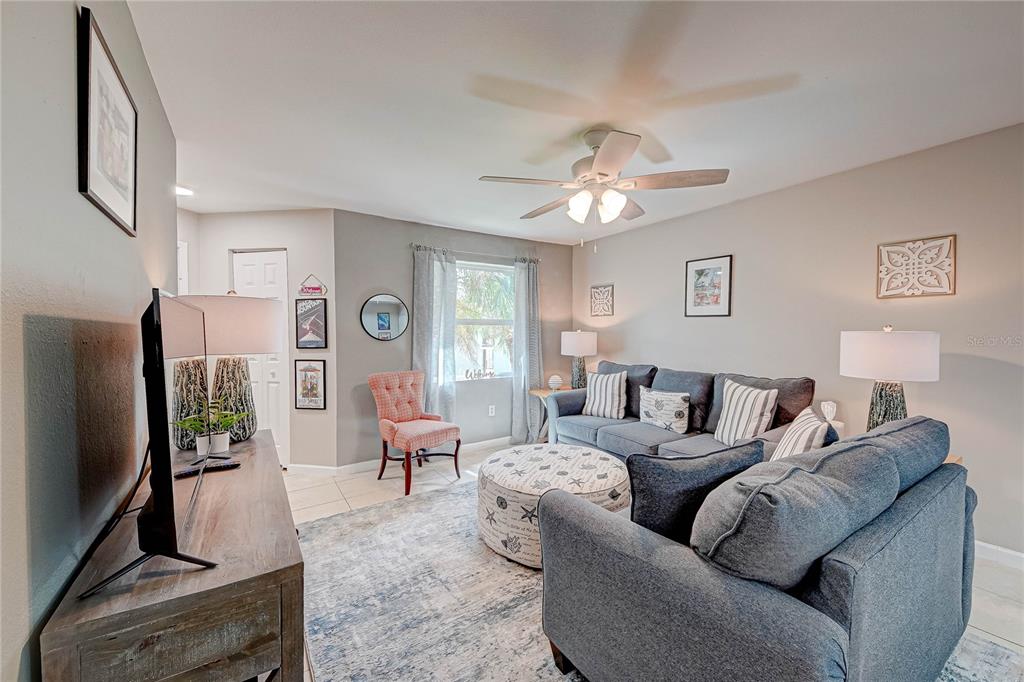 A living room features a gray sofa, a patterned ottoman, and a wooden media console — 3038 PARKWAY BOULEVARD UNIT 305, KISSIMMEE, FL