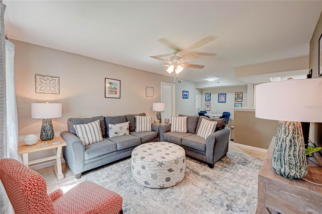 A living room features two gray sofas, a patterned ottoman, and a red armchair — 3038 PARKWAY BOULEVARD UNIT 305, KISSIMMEE, FL