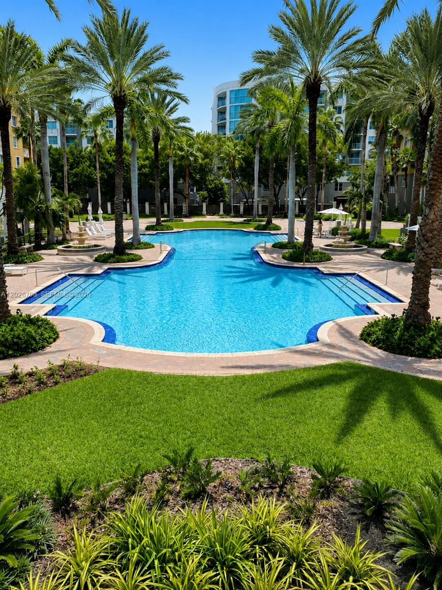 A swimming pool surrounded by palm trees and apartment buildings on a sunny day — 145 Jefferson Ave # 415, Miami Beach FL 33139, MIAMI BEACH, FL