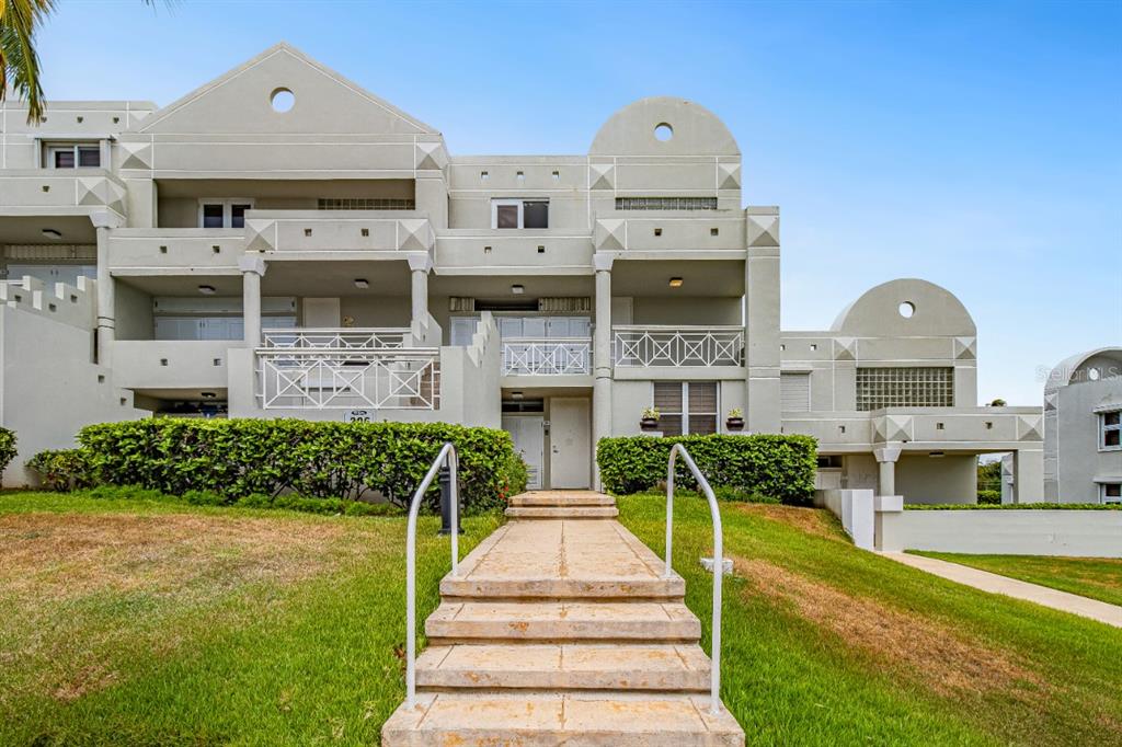 A stone walkway leads to the entrance of a multi-story, light-colored concrete residential building — N St. COND. COSTA DORADA II UNIT L208, DORADO, PR