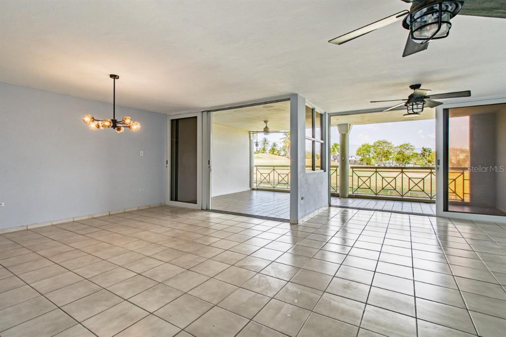 A tiled room features a modern chandelier, ceiling fans, and sliding doors opening to a balcony — N St. COND. COSTA DORADA II UNIT L208, DORADO, PR