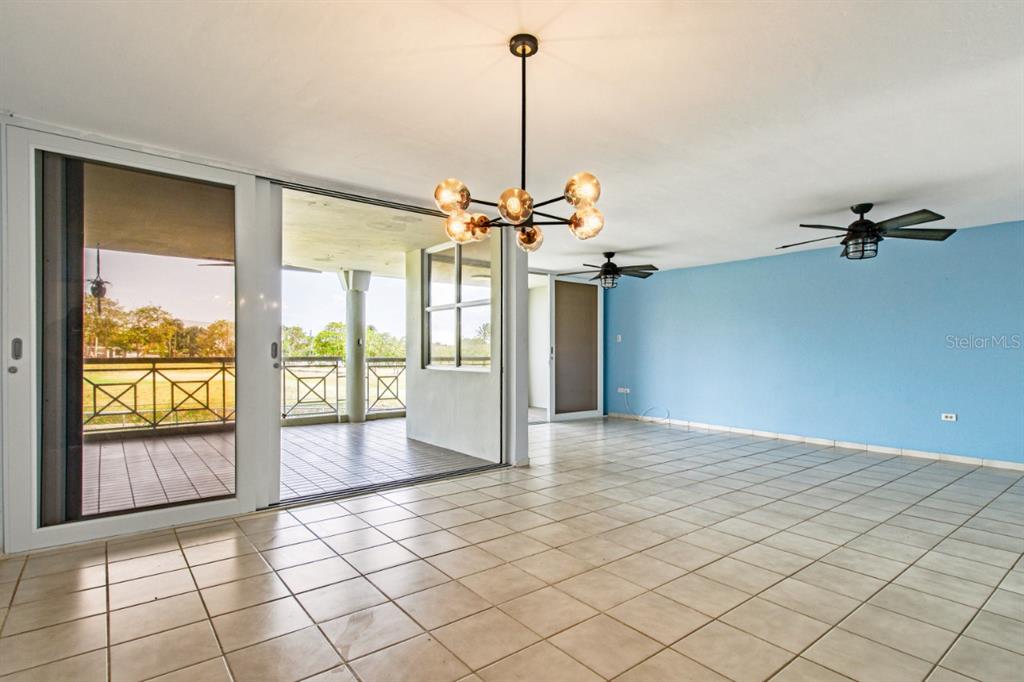 A bright room with tiled floors, a modern chandelier, ceiling fans, and a balcony view — N St. COND. COSTA DORADA II UNIT L208, DORADO, PR