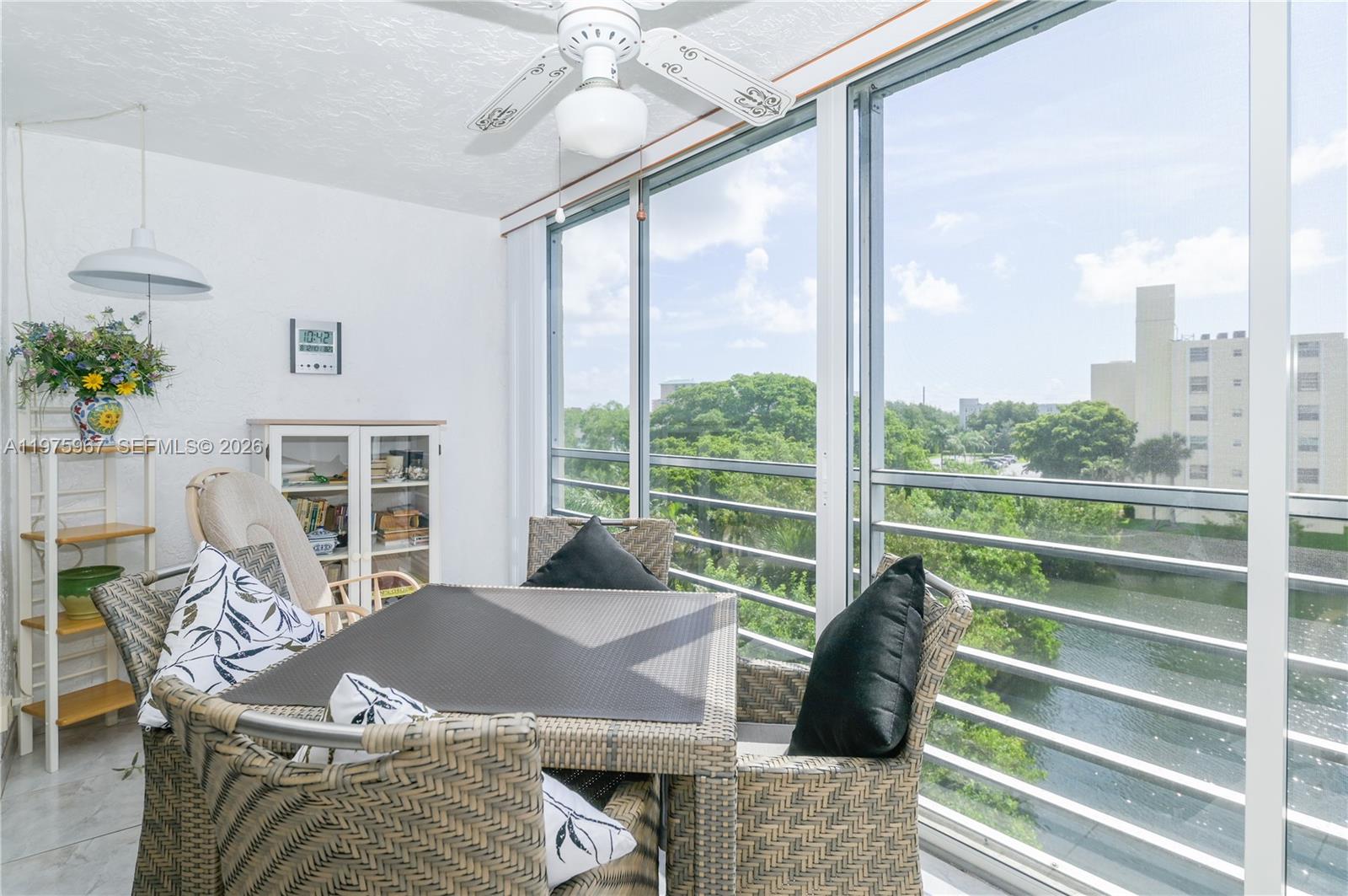 A sunroom features wicker dining furniture, a ceiling fan, and large windows overlooking a canal — 101 SE 3rd Ave # 401, Dania Beach FL 33004, DANIA BEACH, FL