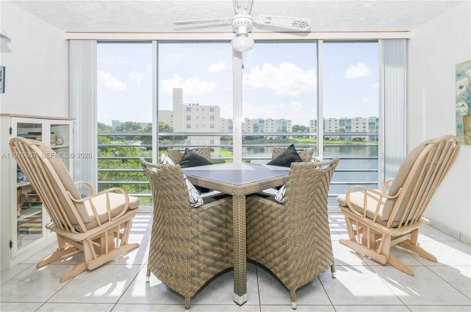 A sunroom features a dining set, two rocking chairs, and floor-to-ceiling windows overlooking water — 101 SE 3rd Ave # 401, Dania Beach FL 33004, DANIA BEACH, FL