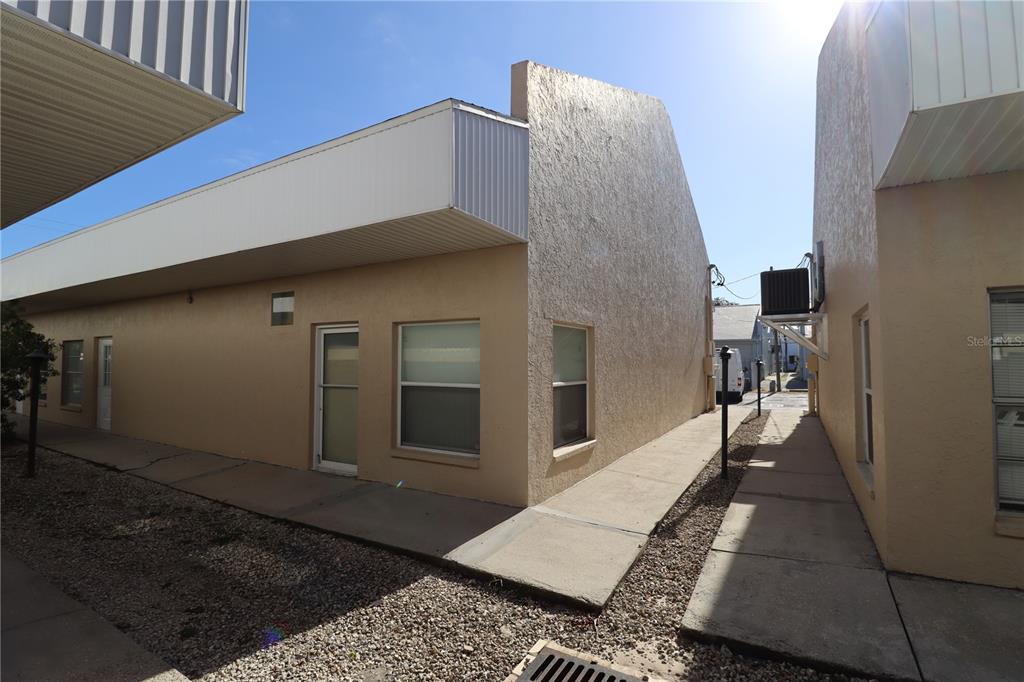 An exterior view of a tan building with a walkway between two units — 18350 PAULSON DRIVE UNIT D-1, PORT CHARLOTTE, FL