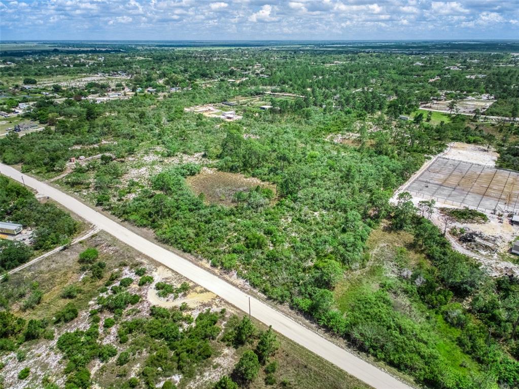An aerial view shows a dirt road bordering a large, undeveloped, brush-covered vacant lot — 125 POLK STREET, LAKE PLACID, FL