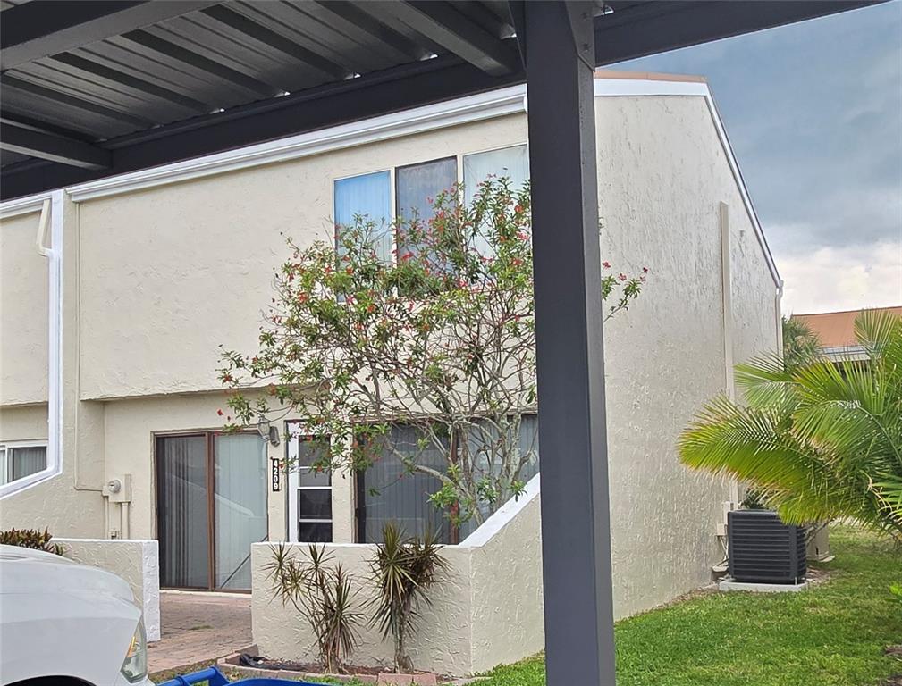A two-story tan stucco townhouse features a small front patio and a covered parking area — 4209 FOGCUTTER COURT UNIT 4209, TAMPA, FL