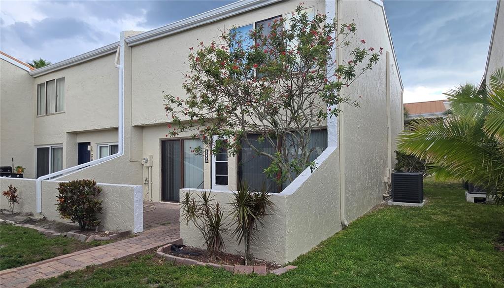 A two-story townhouse exterior features a small patio, a flowering tree, and a grassy yard — 4209 FOGCUTTER COURT UNIT 4209, TAMPA, FL