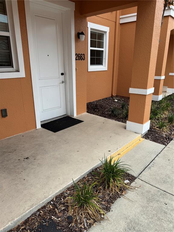 The exterior view shows a white front door, a small porch, and a window — 2663 ROADSTER LANE, KISSIMMEE, FL
