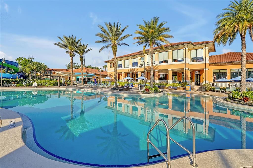 A swimming pool sits in front of a multi-story building with palm trees — 2663 ROADSTER LANE, KISSIMMEE, FL