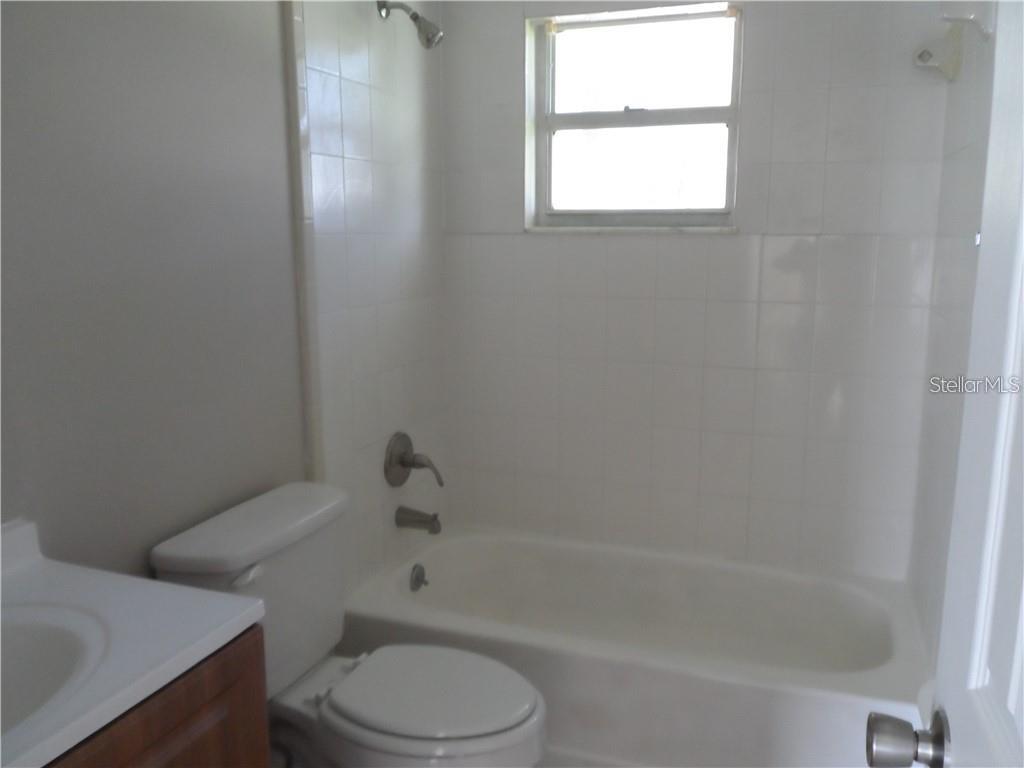 A bathroom features a white toilet, a vanity, and a bathtub with white wall tiles — 602 MCKINLEY COURT, KISSIMMEE, FL