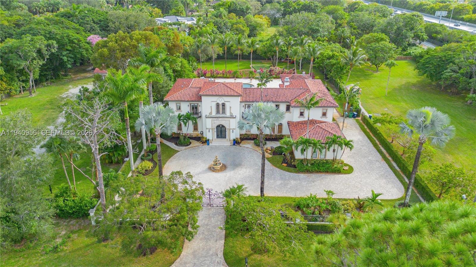 An aerial view shows a large Mediterranean-style house with a circular driveway and fountain — 7538 SW 64th St, Miami FL 33143, MIAMI, FL